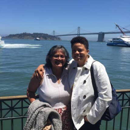 Photo of Elissa and Susan hugging and smiling with the Bay in the background